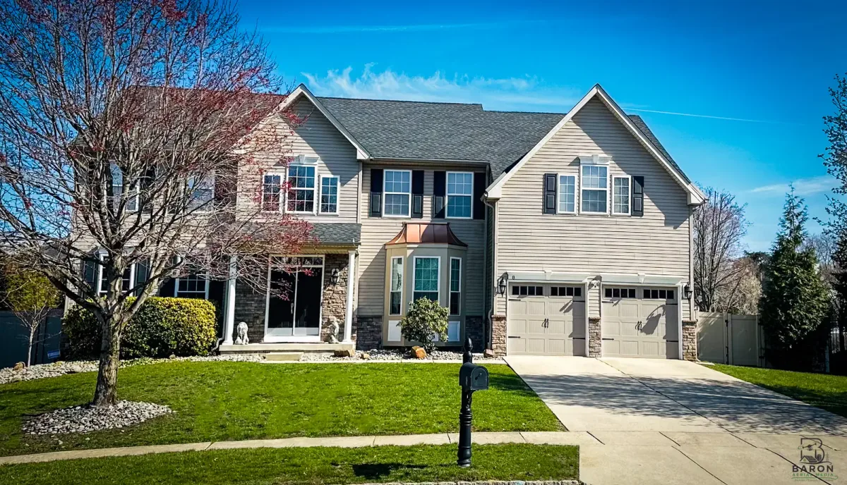 Front of a two-story Hainesport house with driveway, lawn and bare trees