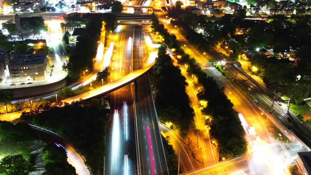 Nighttime highway with vehicle light trails, buildings and illuminated roads