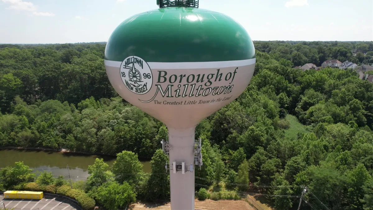 Green Borough of Milltown water tower above a tree canopy