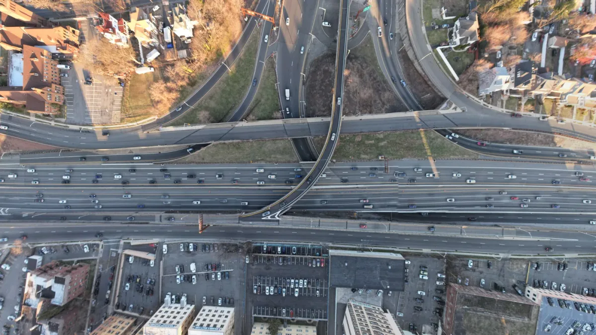 Large highway interchange, curved ramps, road traffic and surrounding development